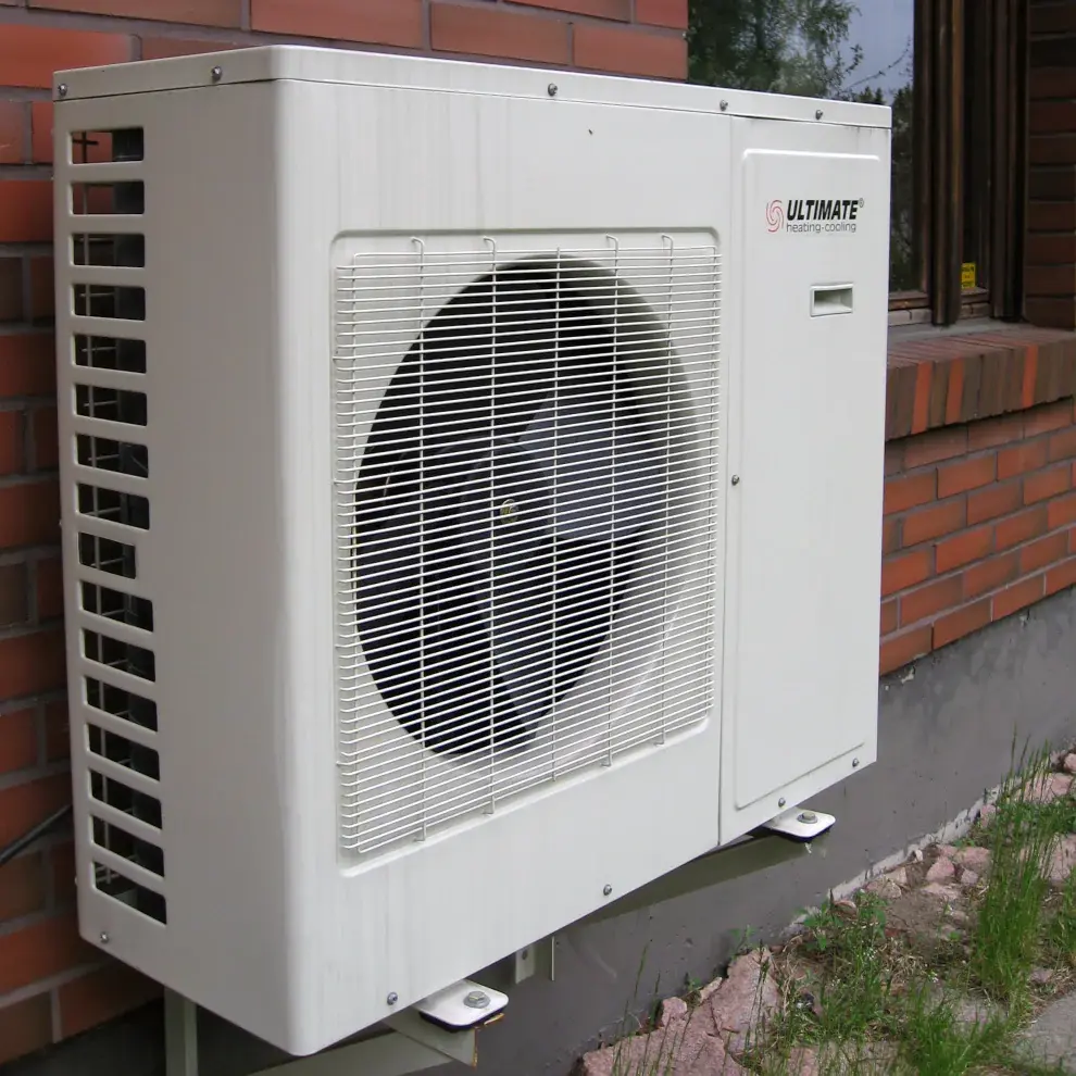 Photo einer Wärmepumpe an einer Haus-Außenwand: ein weißer Metallkasten mit einem großen Ventilator in der Mitte. Nicht schön, aber effektiv.